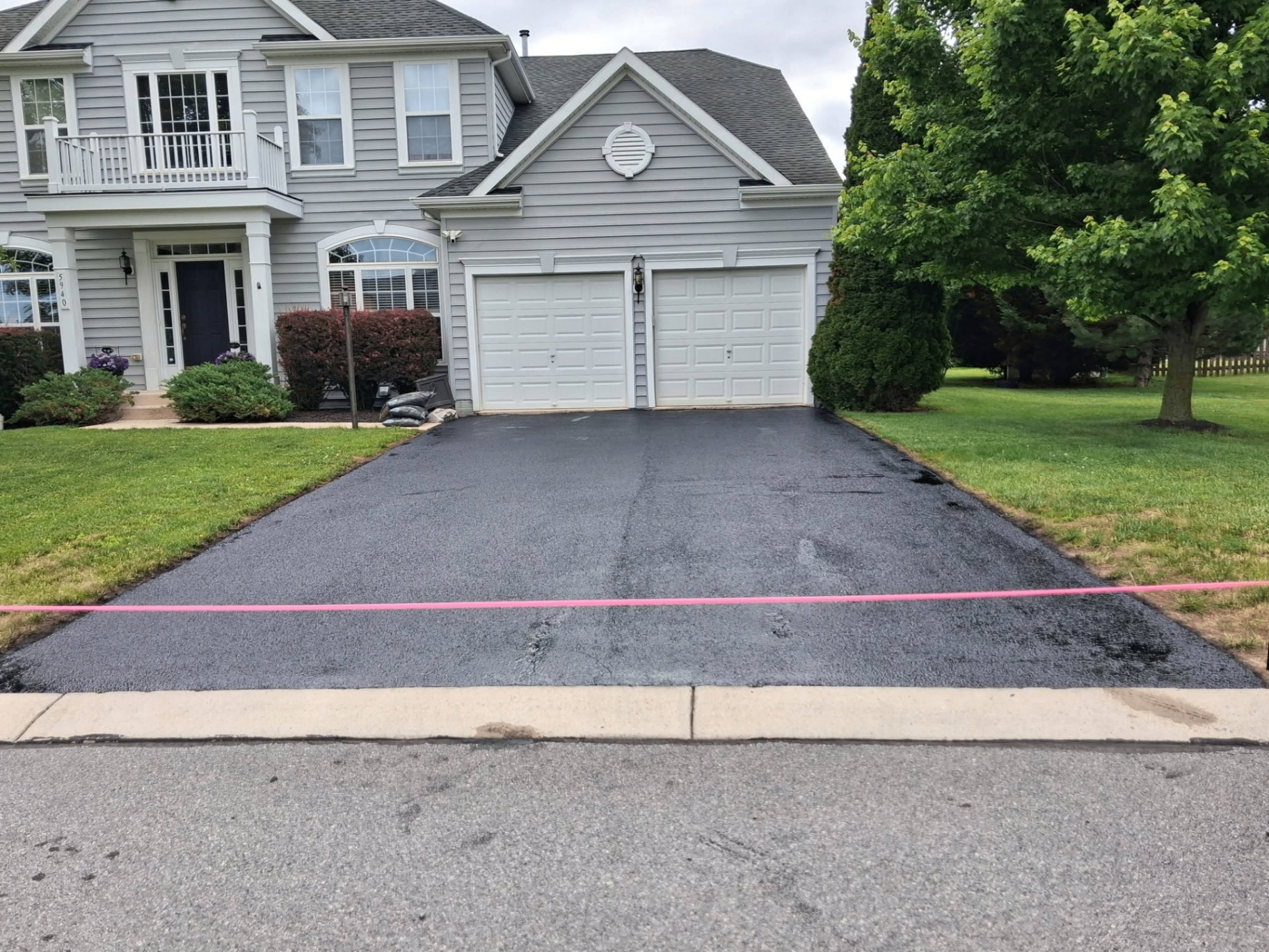 Freshly sealed suburban driveway in front of a two-car garage