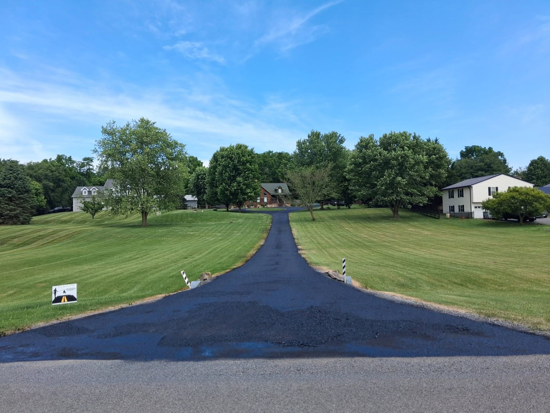 Long rural asphalt driveway freshly paved and sealed leading up to a Central Pennsylvania home